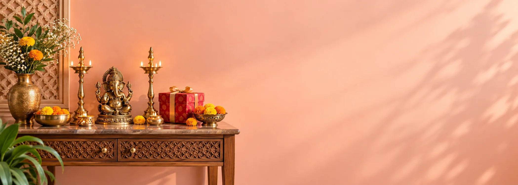 A peach-toned festive setting with a Ganesha idol, brass lamps and marigolds