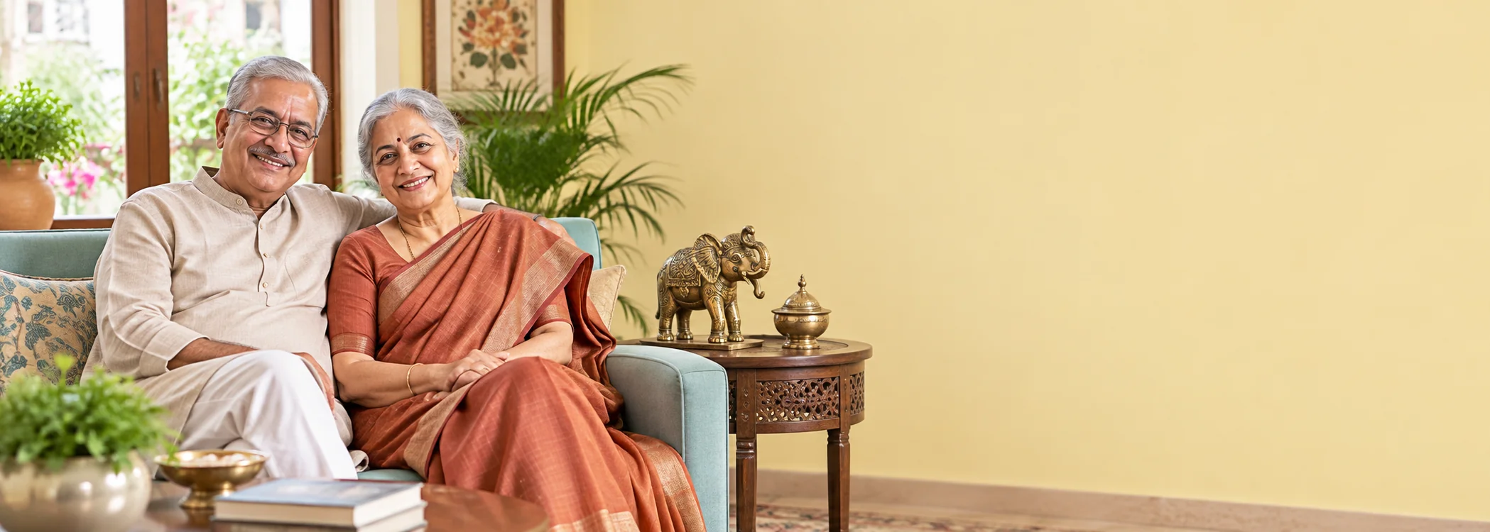 An older couple at home beside a decorative elephant and brass urn