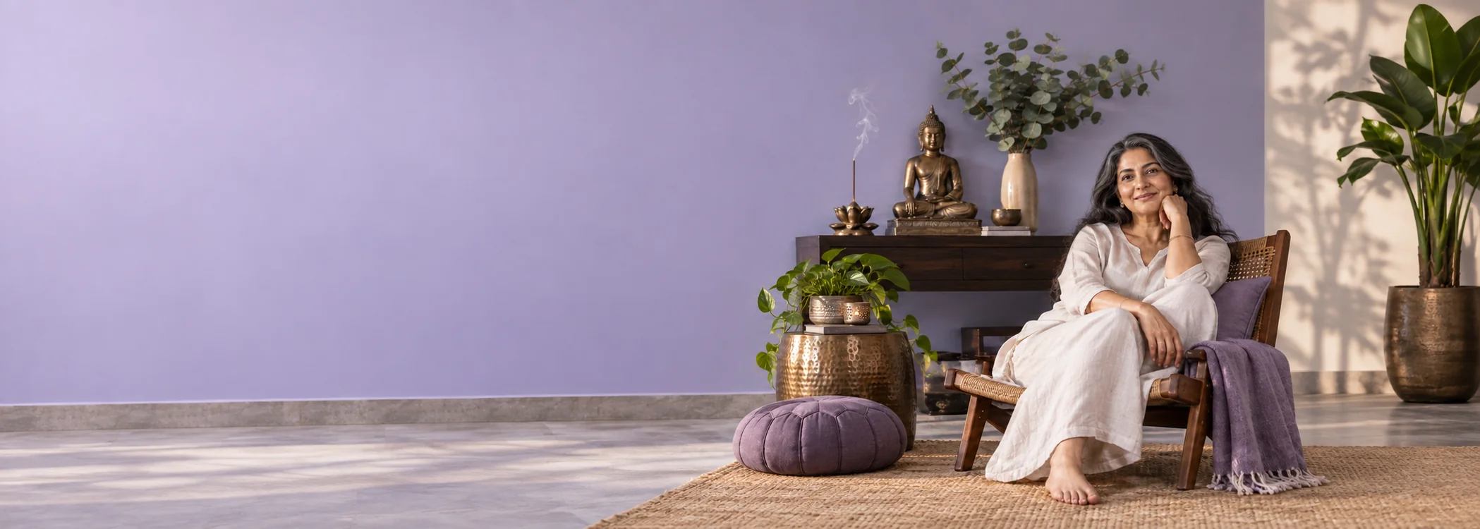 A woman relaxing beside a Buddha sculpture in a lavender meditation corner