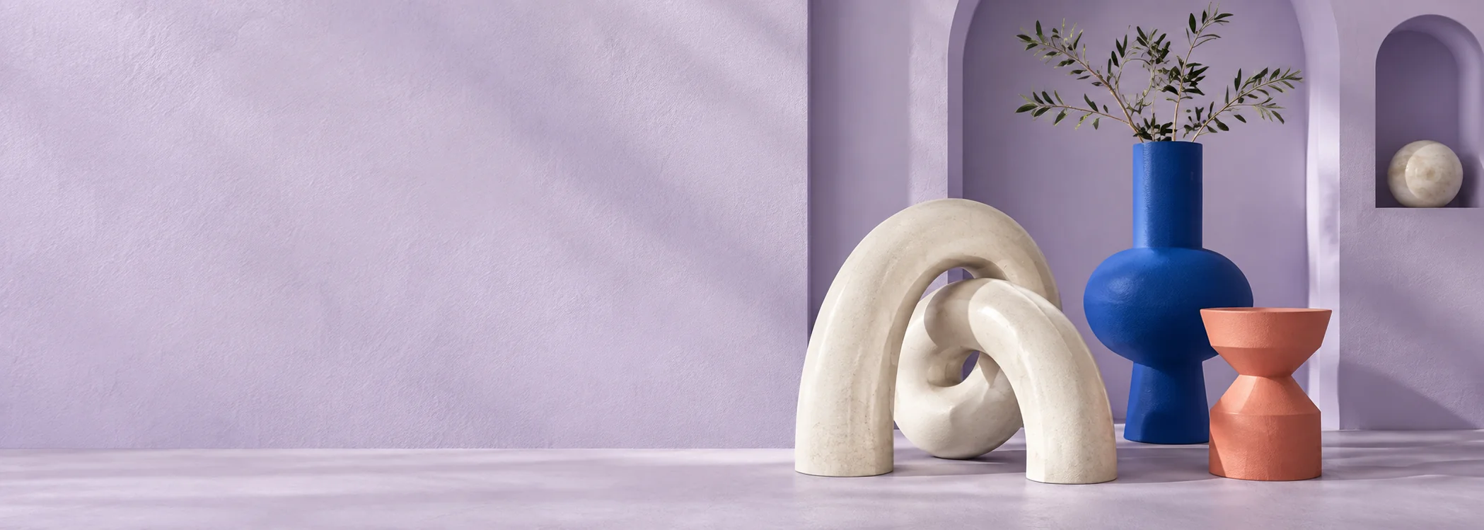Ivory sculptural arcs and cobalt-blue decor against a lilac architectural backdrop